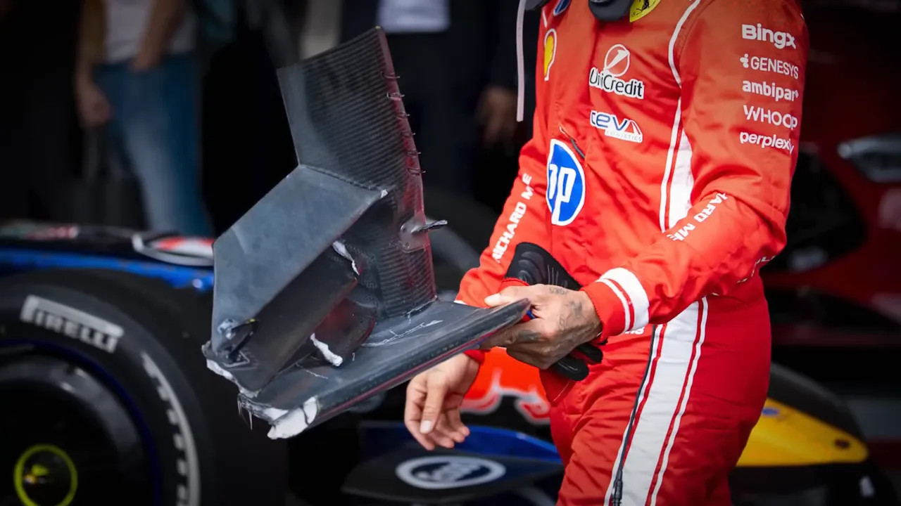 Ferrari driver holding a large piece of damaged car bodywork