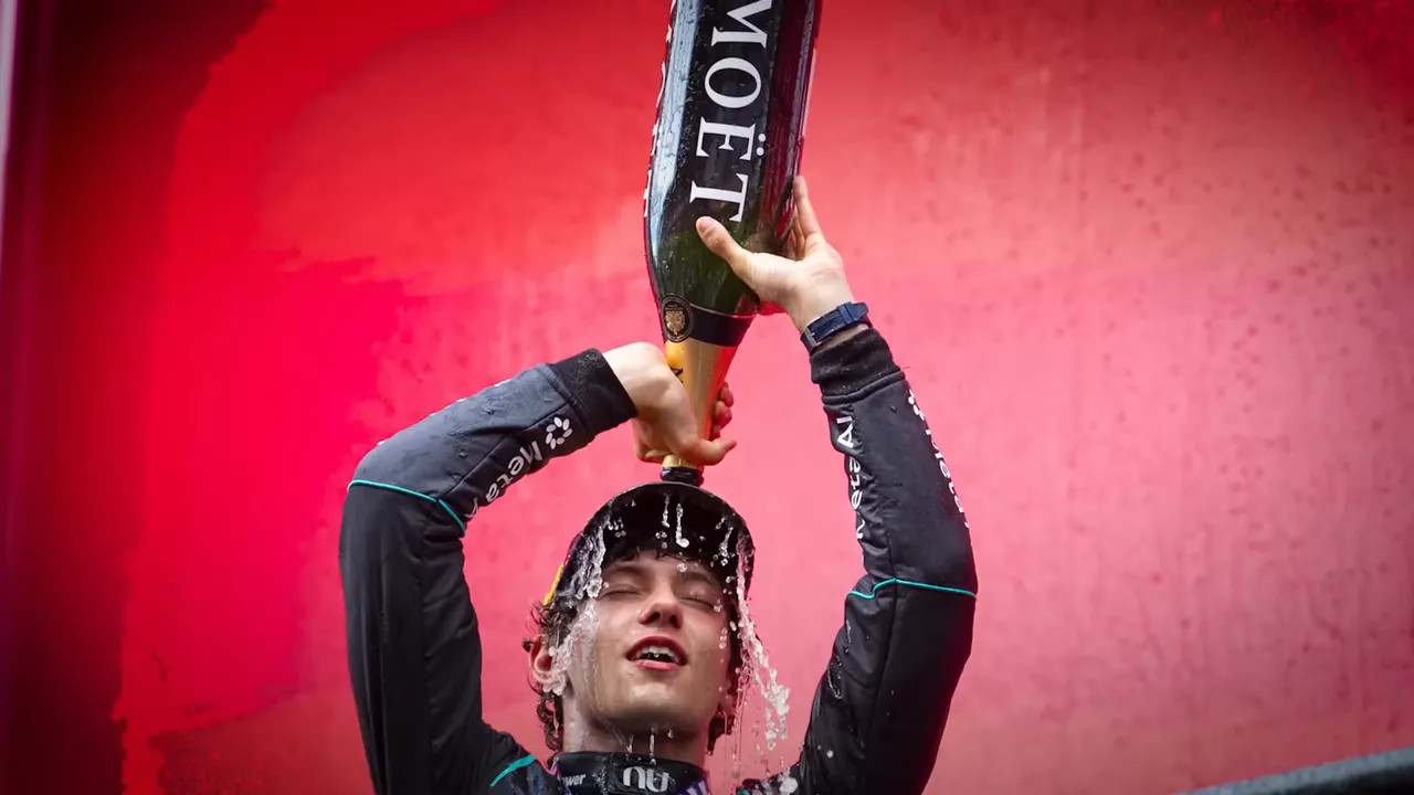Kimi Antonelli lifting a trophy on a red podium backdrop