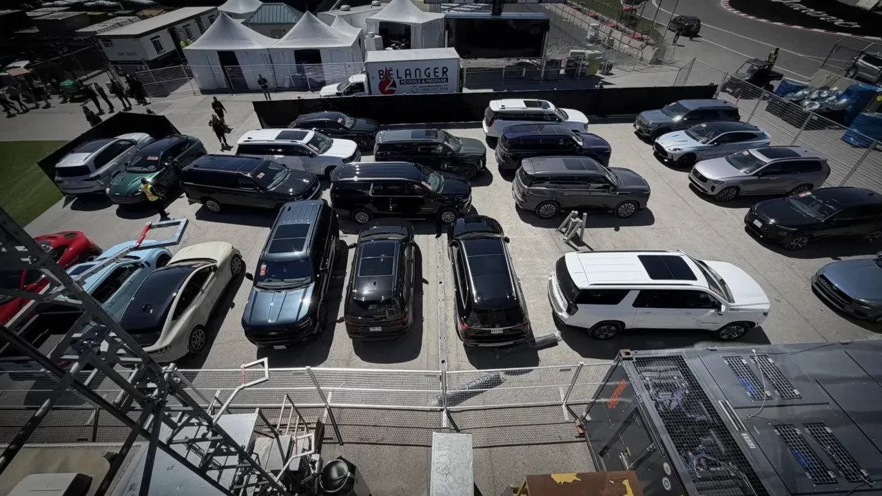 High-angle view of cars lined up in a fenced paddock parking area during Canadian Grand Prix media day