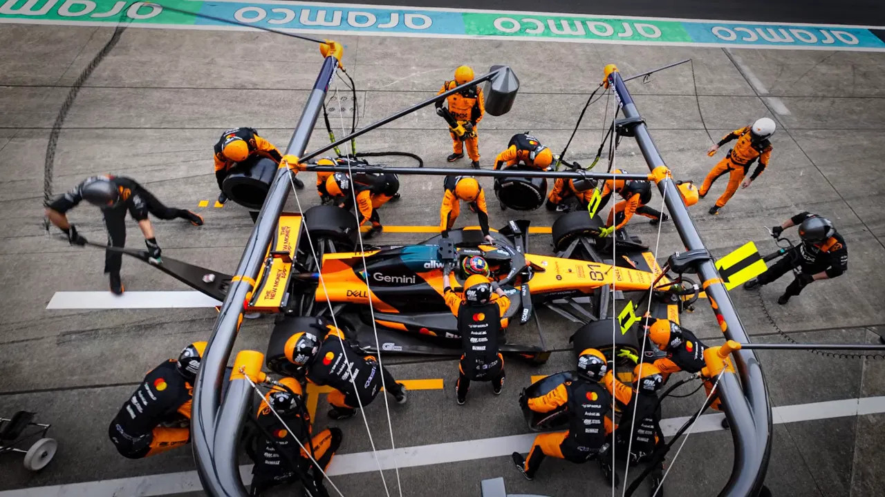 Pit crew working on an orange Formula 1 car in the pit lane