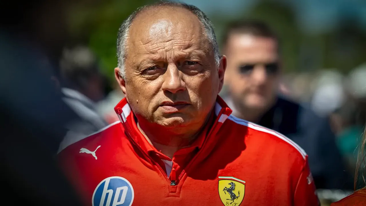 Ferrari team principal-style official in a red jacket looking serious