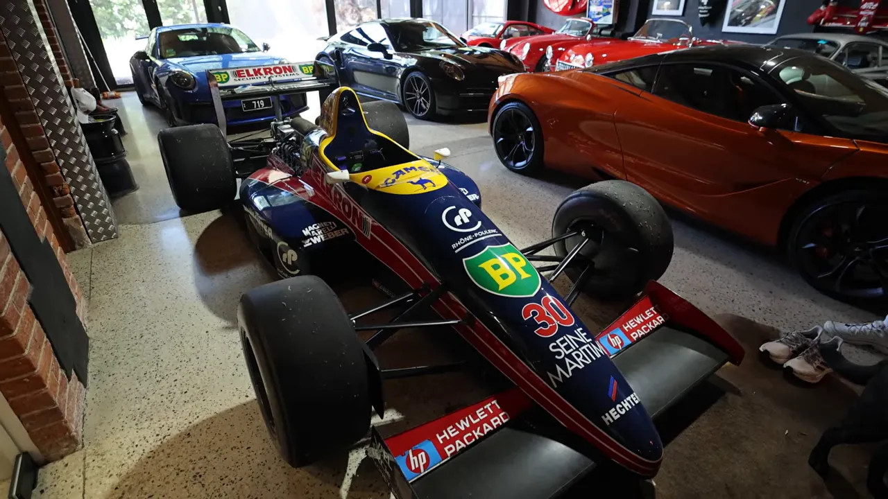 Restored 1988 Lola Formula 1 car on display in a garage with other cars around it
