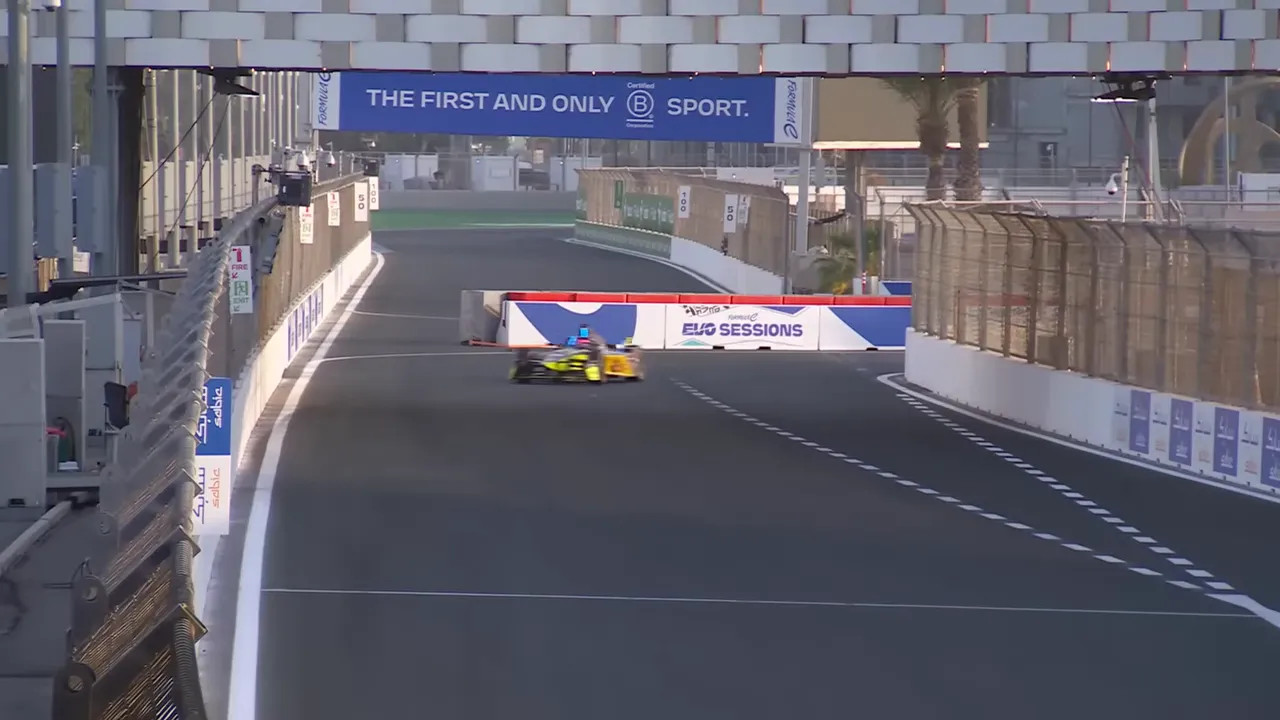 Formula E single-seater cornering on the Jeddah street circuit with concrete barriers and EVO Sessions signage