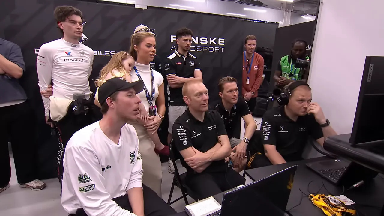 Group of creators and team engineers gathered around laptops and monitors in the paddock garage reviewing telemetry and setup.