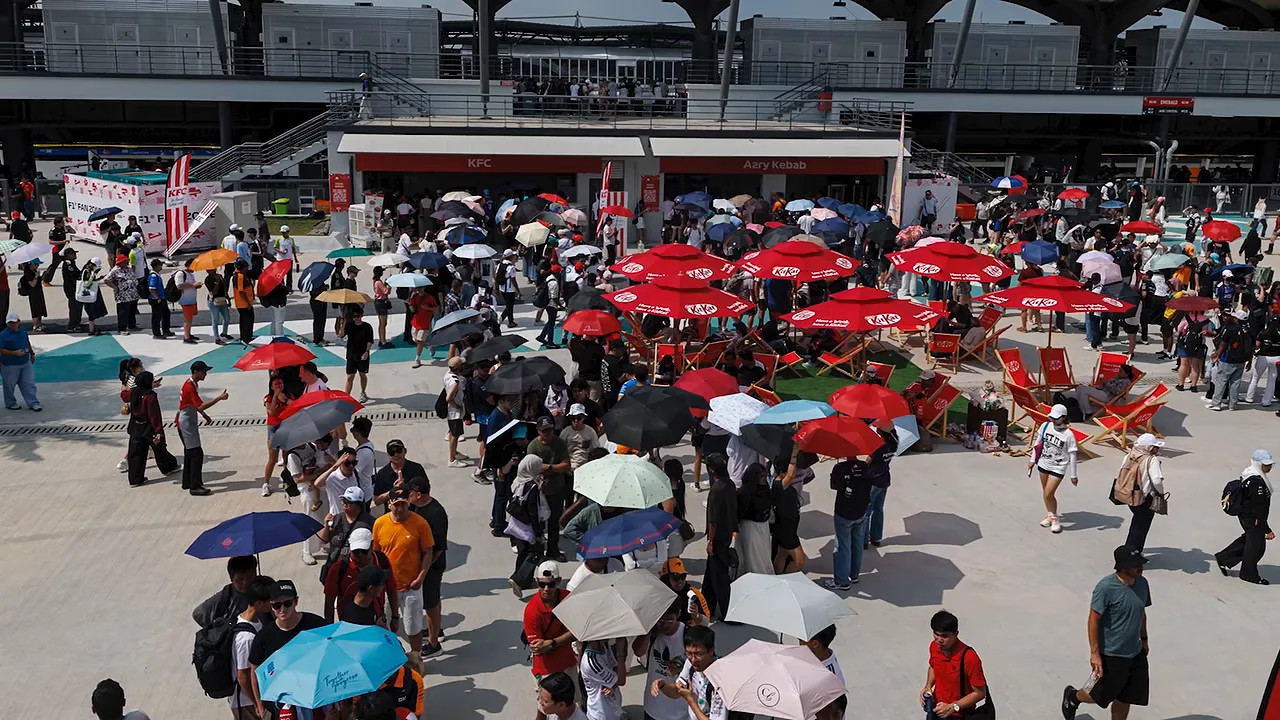 A large crowd outside the circuit with many people sheltering under umbrellas