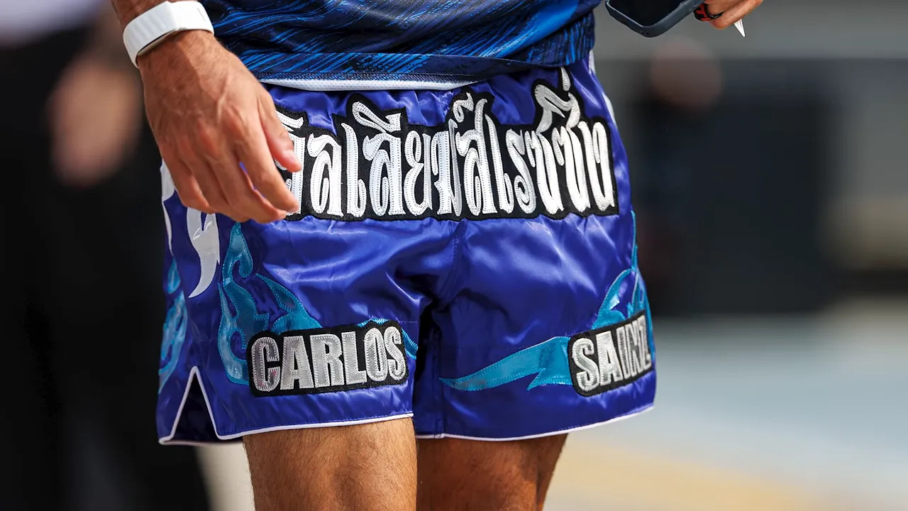 Close-up of blue Muay Thai shorts with Thai lettering and Carlos and Sainz name patches