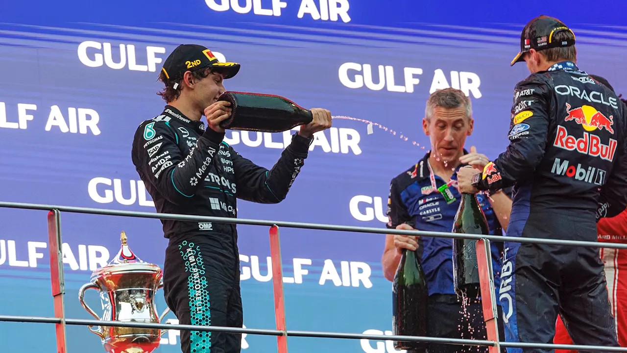 Drivers and a Red Bull representative holding bottles during the podium celebration