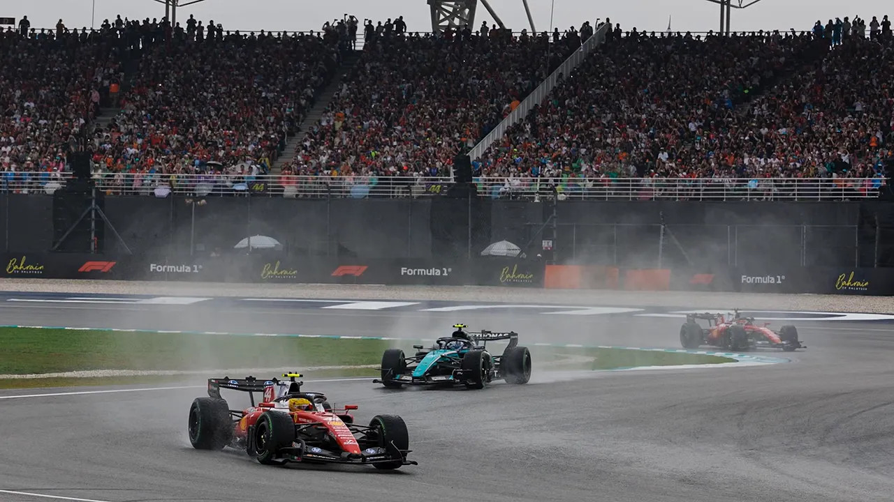 Formula 1 cars racing through a wet corner with spray behind them