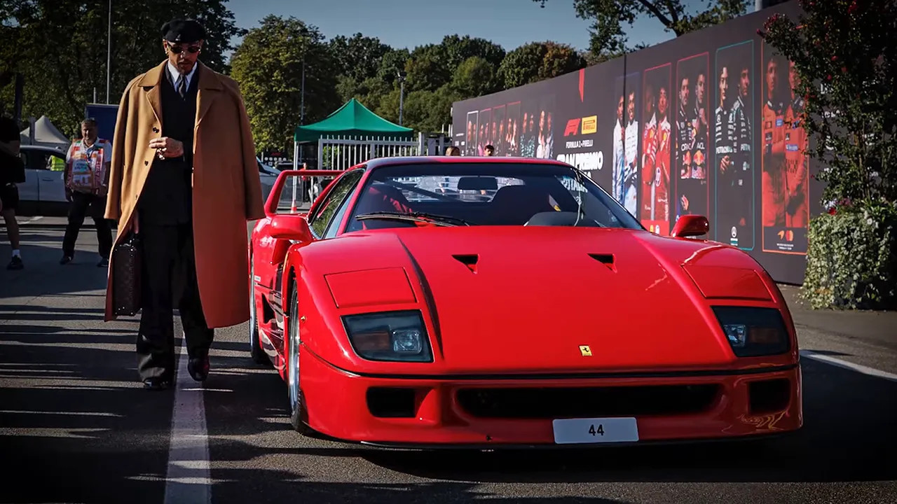Lewis Hamilton standing beside a red Ferrari F40 at the Monza paddock entrance