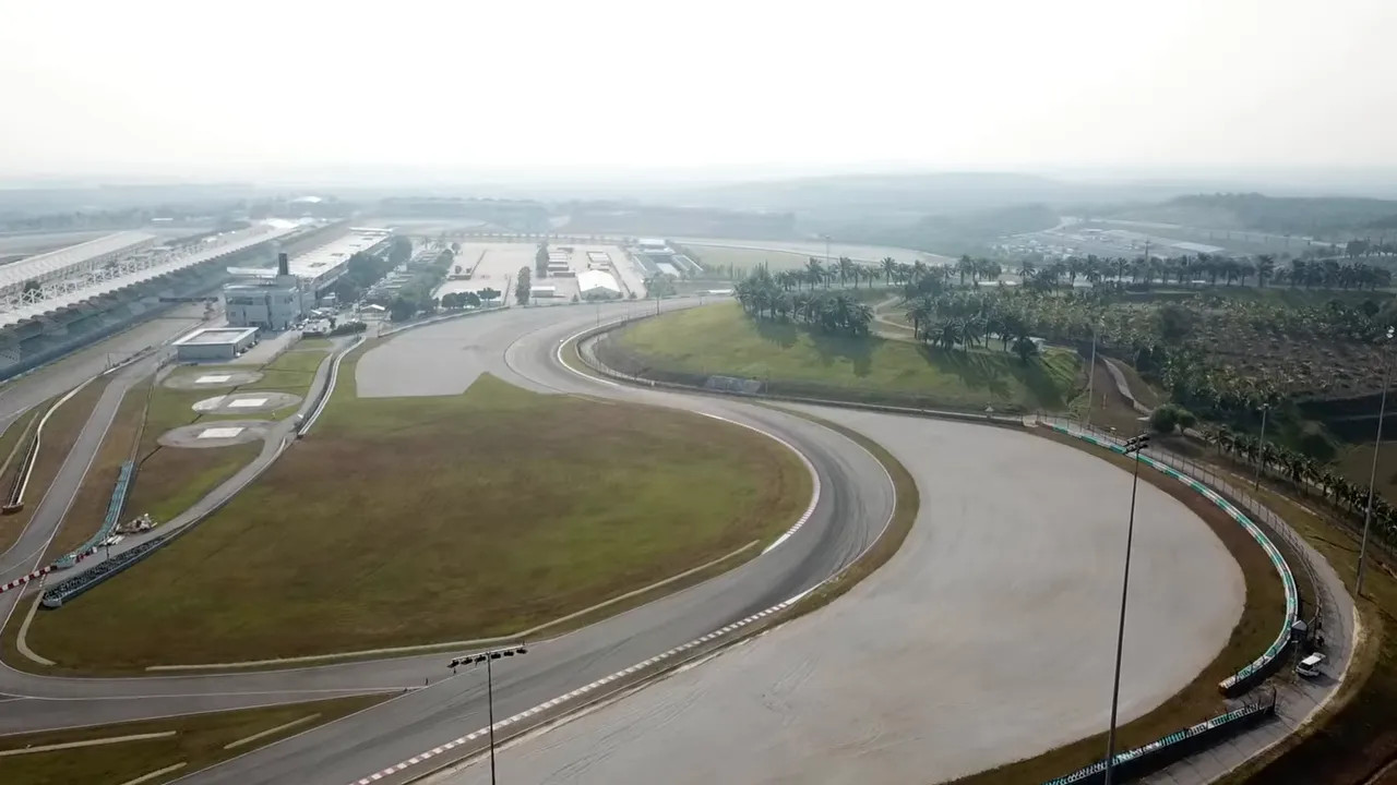 Aerial view of a broad Sepang circuit corner, surrounding track and grandstands