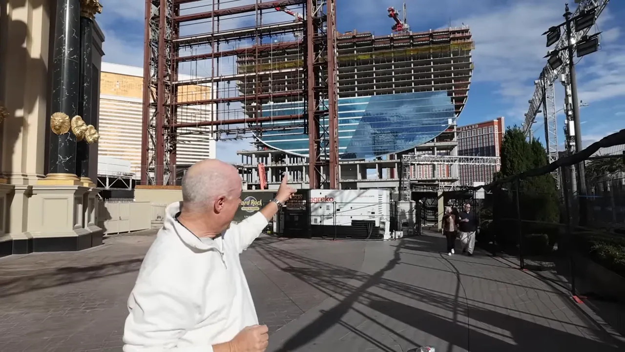 Construction site on the Las Vegas Strip with a man pointing toward a partially completed guitar-shaped tower and cranes in the background.