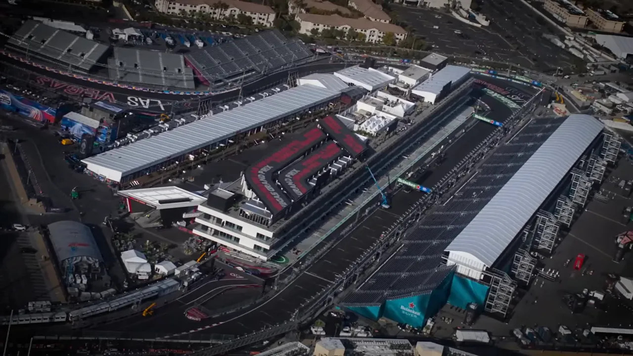 High-angle aerial view of the Las Vegas F1 paddock, pit lane and large temporary grandstands along the Strip.