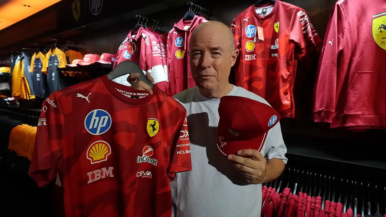 Presenter holding a red Ferrari team shirt and matching cap in the merchandise shop.