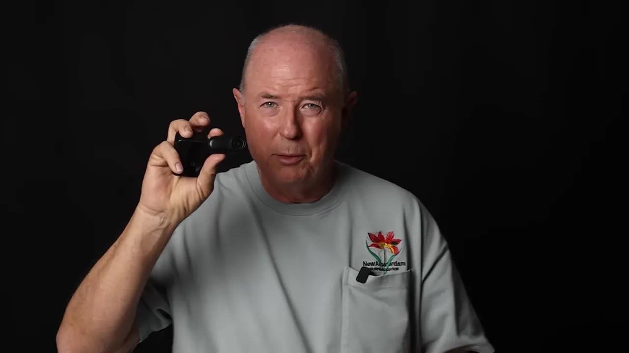 Clear view of a compact action camera held up by the presenter on a dark studio background