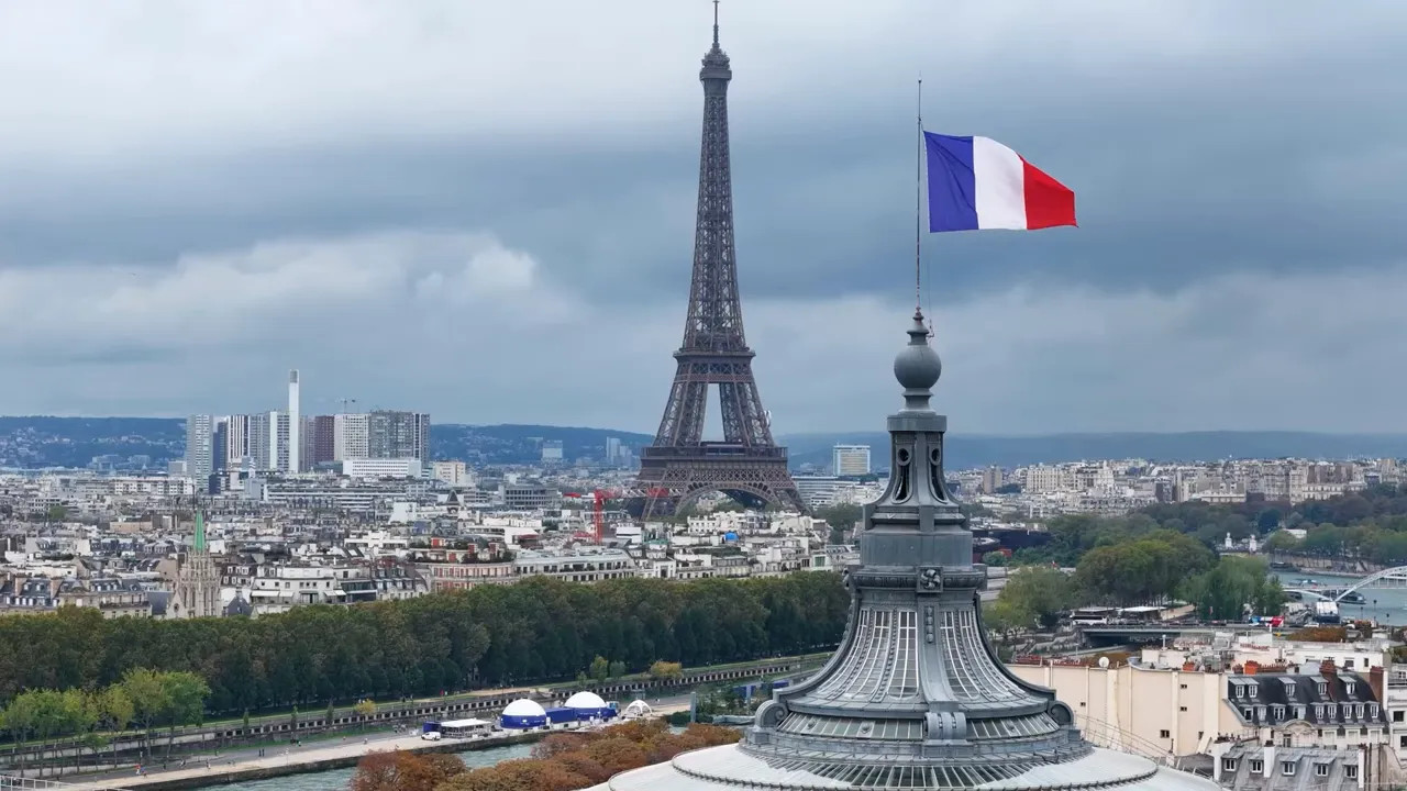 French flag flying with the Eiffel Tower in the background