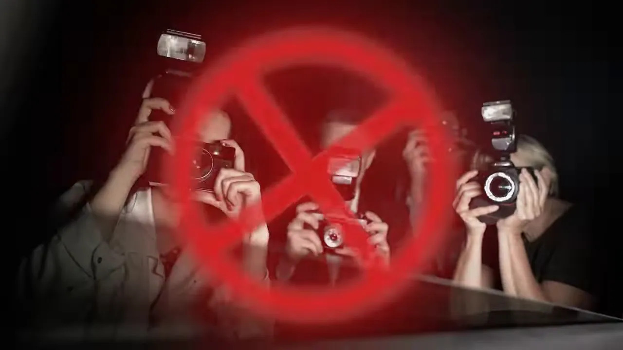 Photographers with cameras covered by a large red prohibition symbol