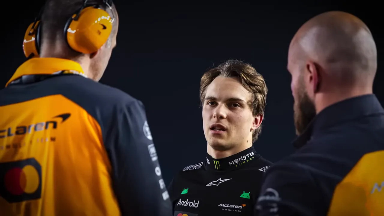 McLaren driver in race suit talking with team engineers in the garage