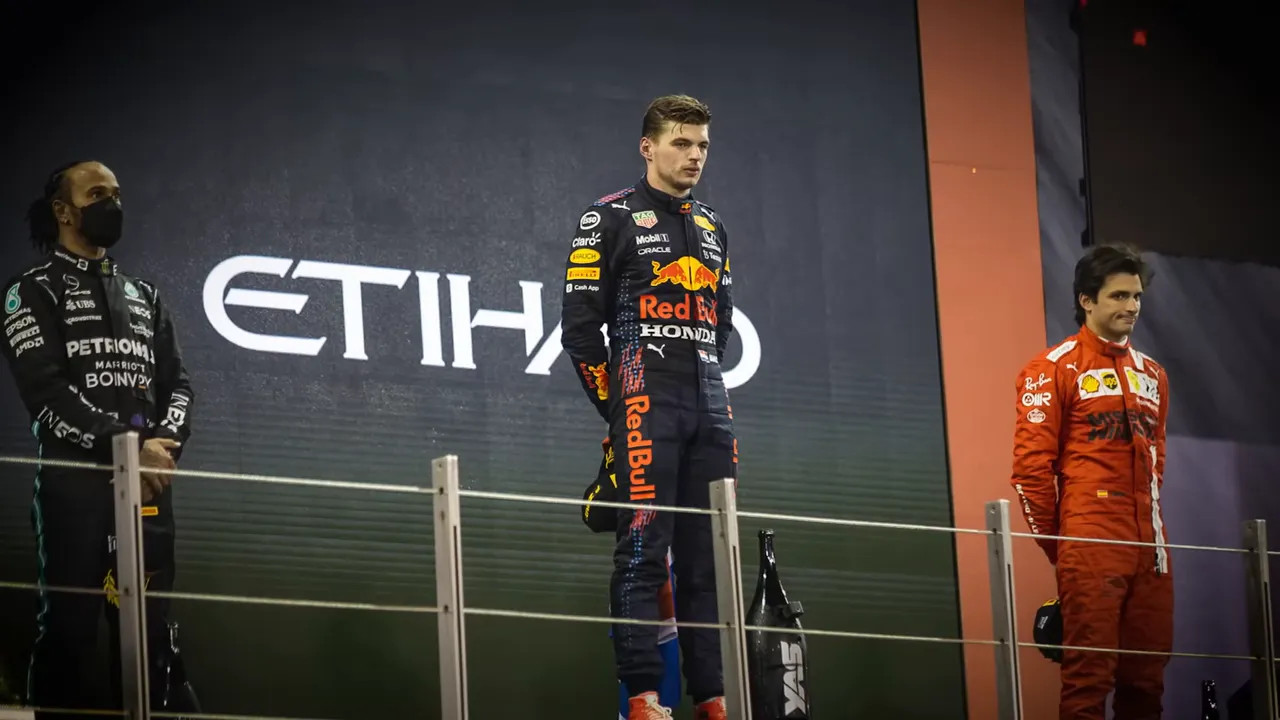 Race winner standing on the top step of the podium with the runners‑up either side during the trophy ceremony.