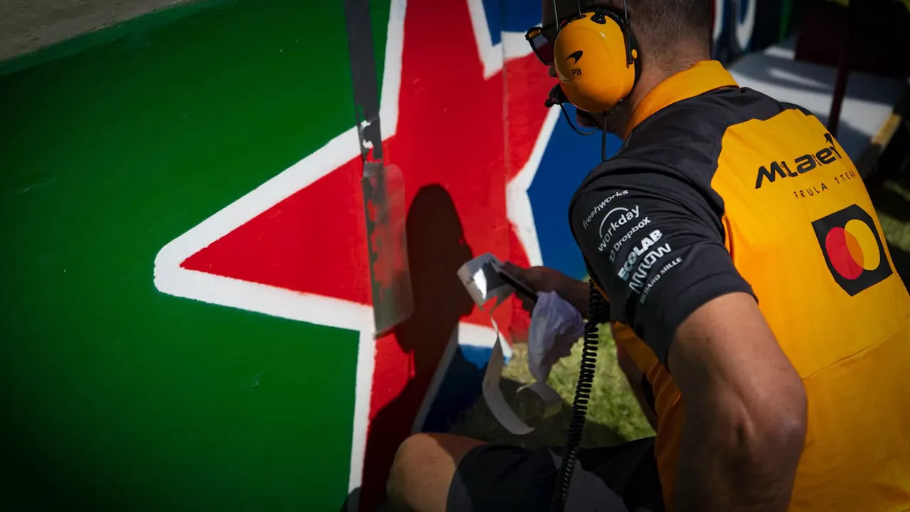 Crew member applying tape to the wall ahead of the formation lap