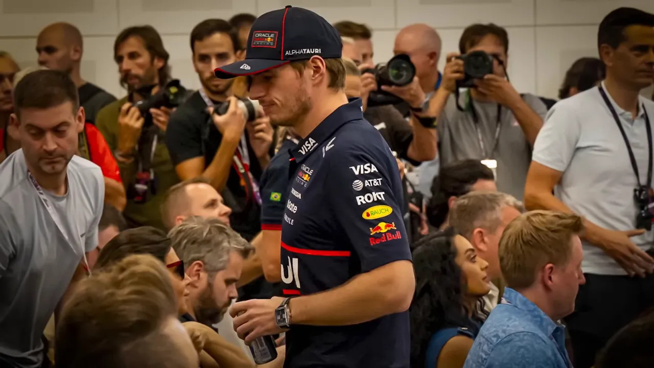 Max Verstappen in a press room with photographers and media crowd behind him
