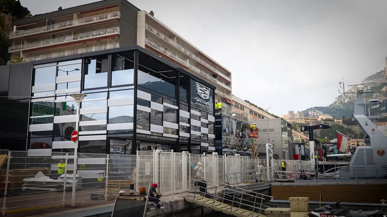 Large glass and black hospitality building beside the Monaco harbour and circuit fencing