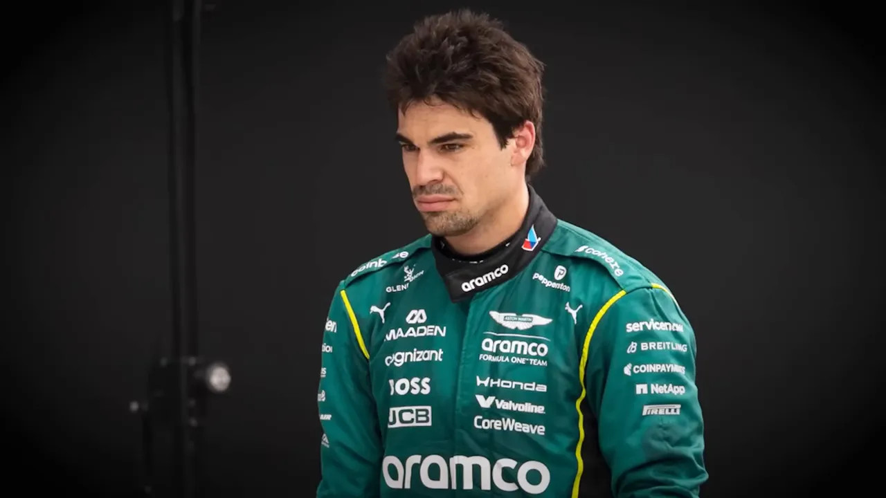 F1 driver in Aston Martin-style team gear standing on a trackside interview backdrop