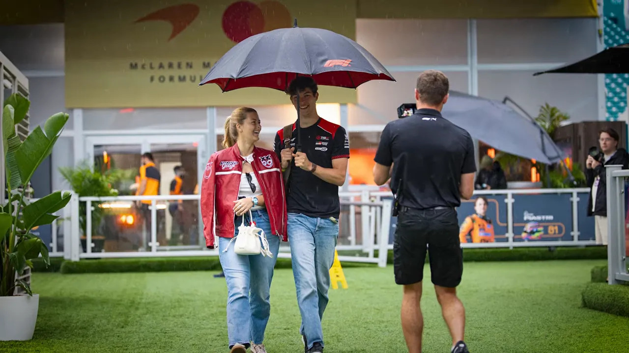 Driver and paddock staff walking under an umbrella in the Miami GP hospitality area
