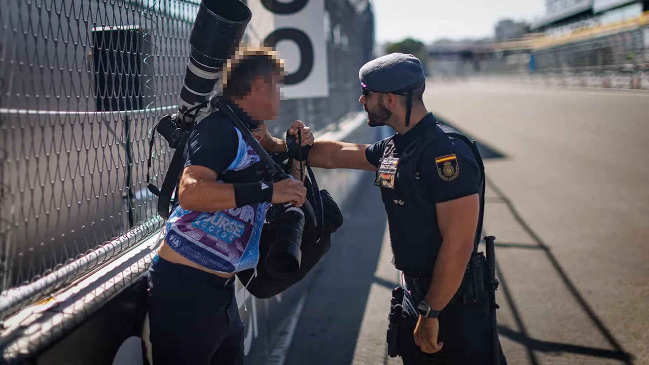 Photographer speaking with a police officer beside circuit fencing