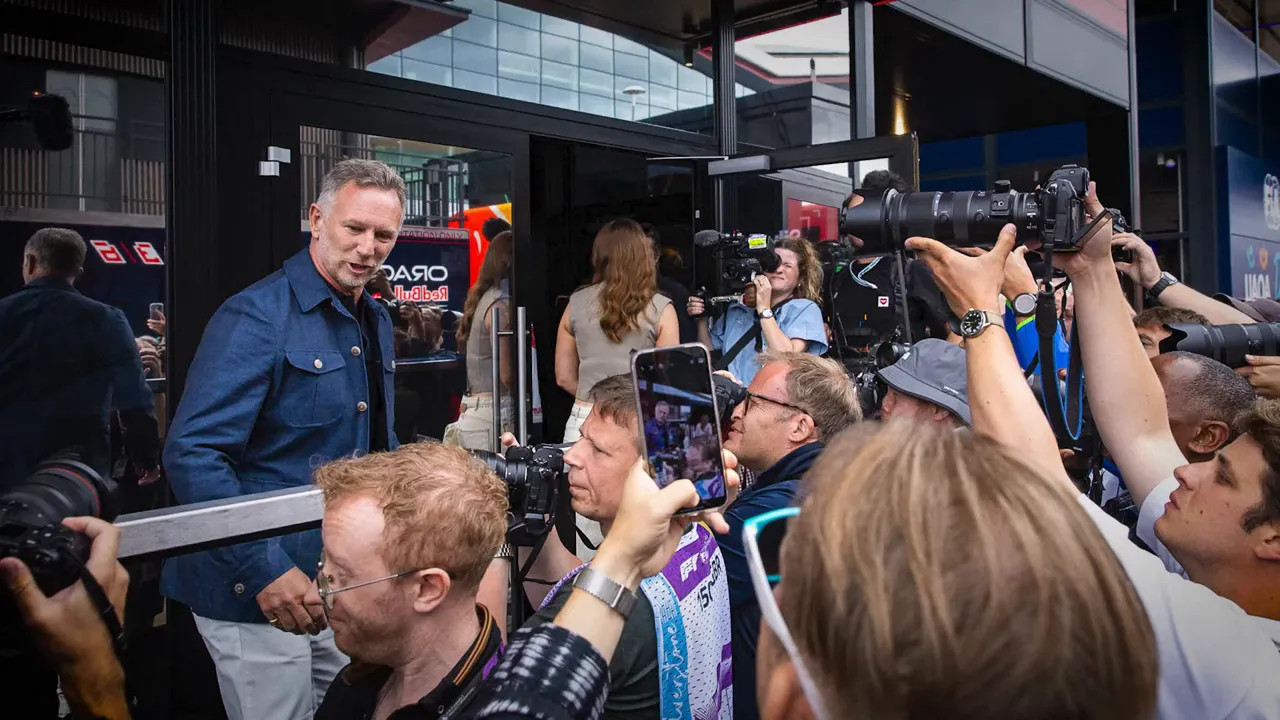 Christian Horner surrounded by photographers and phones outside a paddock building