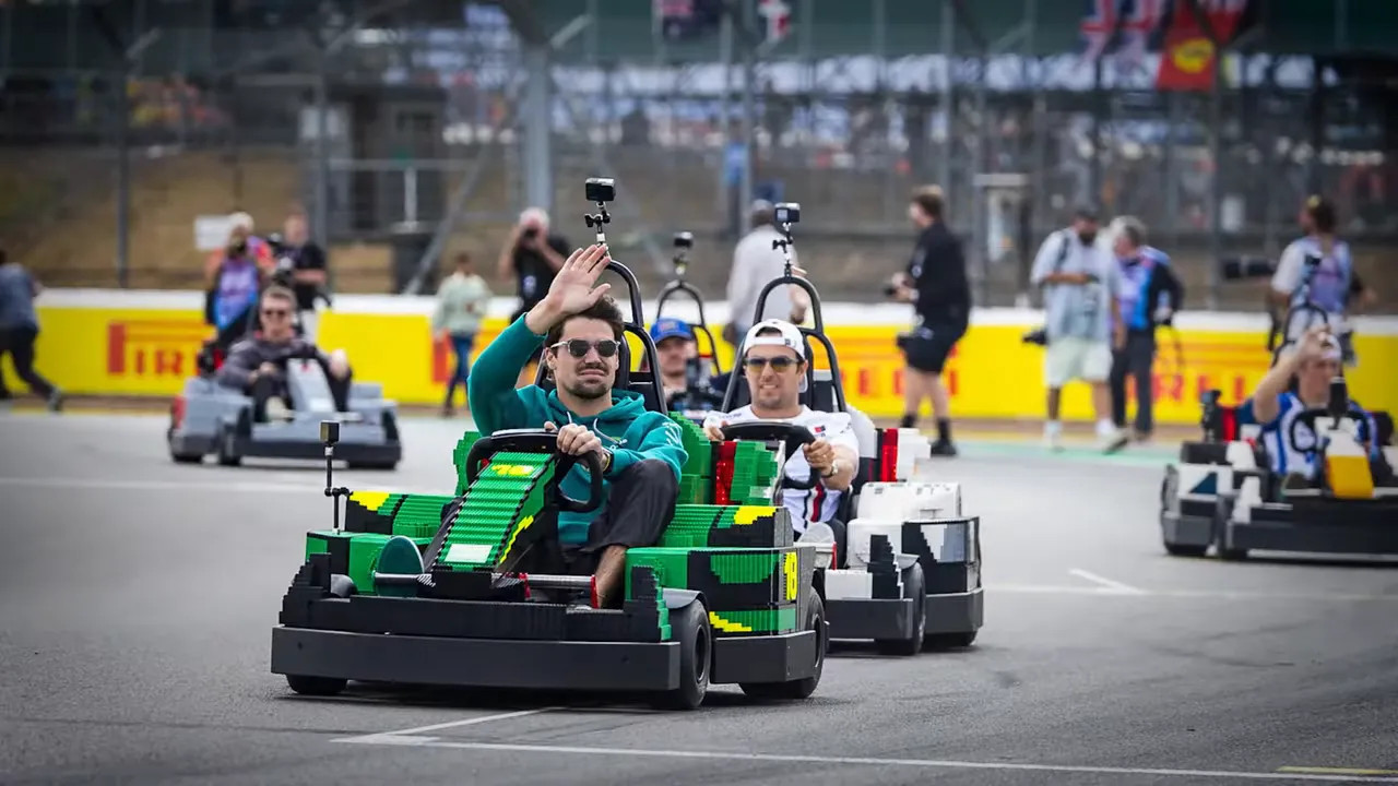 Several drivers racing Lego-style go-karts on track with one driver waving