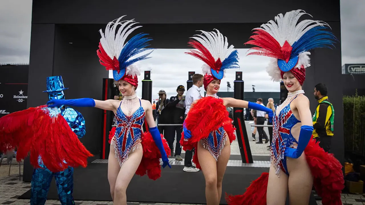 Three performers in red white and blue feather costumes standing in the paddock