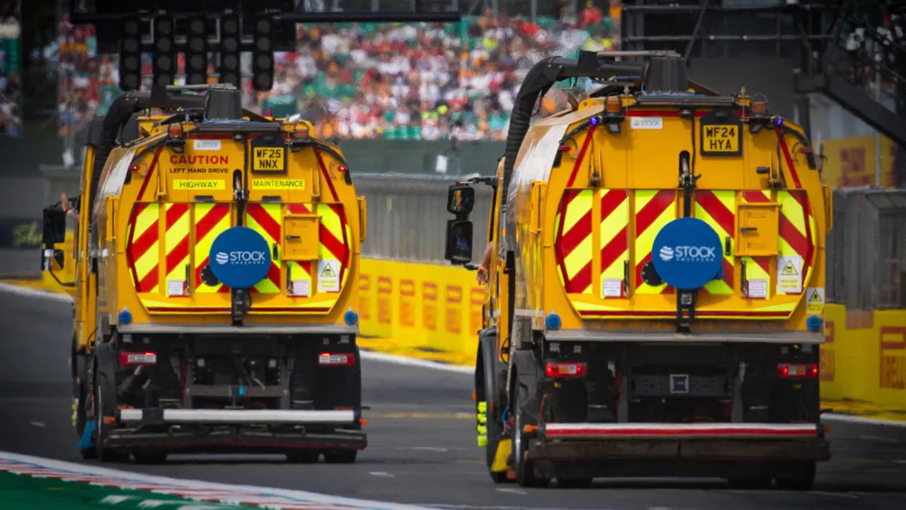 Two yellow track cleaning vehicles driving down the circuit