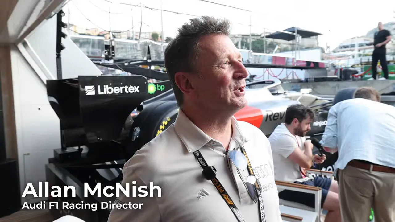 Allan McNish speaking on the yacht with an Audi Formula 1 show car behind him