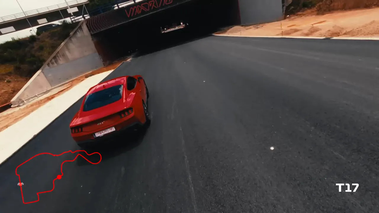 Red car entering a dark tunnel beneath a bridge on the circuit