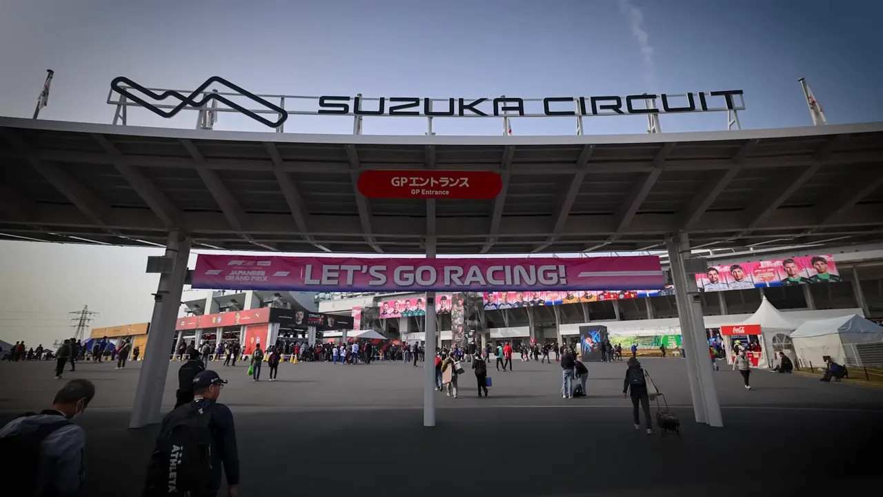 Entrance to Suzuka Circuit with 'LET'S GO RACING!' banner and grandstand beyond