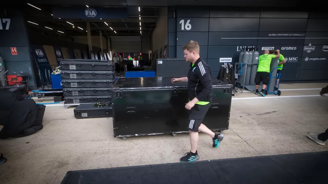Large black transport crates on wheels outside garage 16 with team members working nearby
