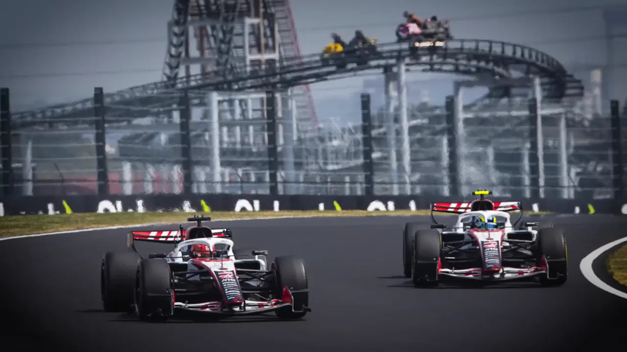 Two F1 cars battling on track while other cars follow at speed